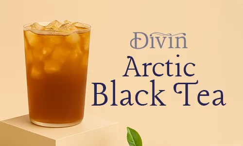 a glass of iced divin arctic black tea on a podium with fresh tea leaves on the side