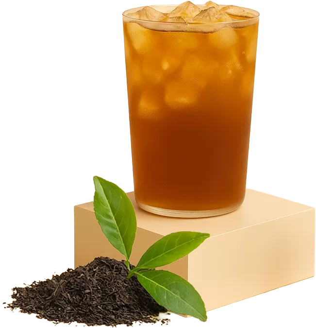 a glass of iced black tea on a podium with fresh assam tea leaves and green leaves beside it
