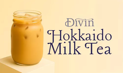 A mason jar filled with iced Hokkaido Milk Tea placed on a podium with beige background and the text “Divin Hokkaido Milk Tea.”